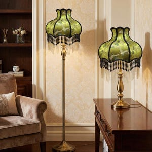 May include: A floor lamp and a matching table lamp, both featuring brass-toned metal stands and bell-shaped shades in a vibrant lime green fabric with a bird pattern, finished with black scalloped trim and long, dangling black beaded fringe.