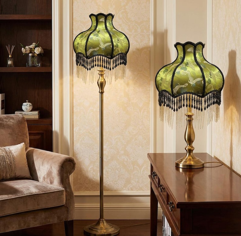 May include: A floor lamp and a matching table lamp, both featuring brass-toned metal stands and bell-shaped shades in a vibrant lime green fabric with a bird pattern, finished with black scalloped trim and long, dangling black beaded fringe.