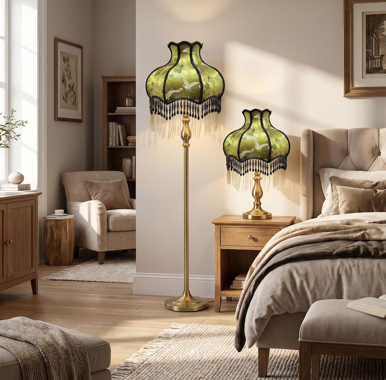 May include: A floor lamp and a matching table lamp, both featuring a brass-toned metal base and a bell-shaped green fabric shade with a bird pattern, finished with a decorative black beaded fringe trim along the bottom edge of the lampshades.