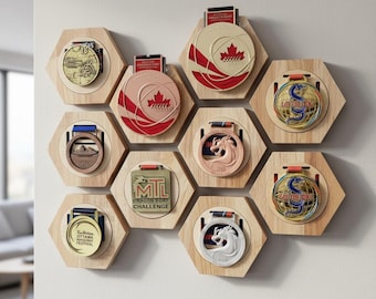 May include: A collection of nine hexagonal light-colored wooden medal display mounts arranged in a honeycomb pattern on a wall. Each mount holds a unique circular or square medal with various designs, including maple leaves, dragons, and text.