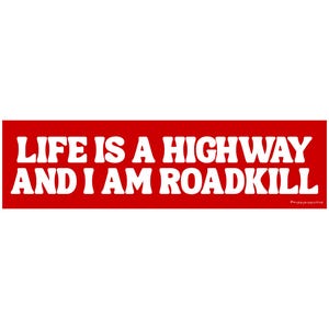 May include: A rectangular sticker with a red background and white text. The text reads "LIFE IS A HIGHWAY AND I AM ROADKILL". The sticker also includes a small text at the bottom right corner.
