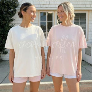 Può includere: Due donne indossano magliette e pantaloncini. Una donna indossa una maglietta color crema e pantaloncini rosa. L'altra donna indossa una maglietta rosa e pantaloncini bianchi. Il testo "coconut coffee mockups" è sulle magliette.