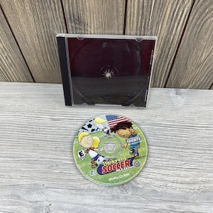May include: A Backyard Soccer MLS Edition CD-ROM game disc with a black CD case. The disc features cartoon characters playing soccer with an American flag in the background. The game is for Win/Mac.