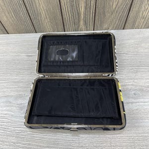 May include: Open wallet with a black interior and a patterned exterior. The exterior features a mix of black, white, and yellow patterns. The interior has multiple card slots and a clear ID window.