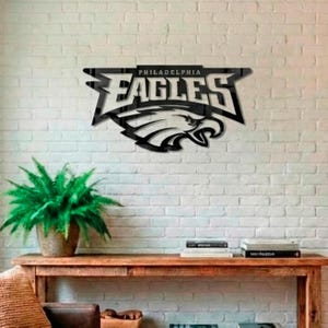 Puede incluir: Arte mural de metal negro con el logotipo de los Philadelphia Eagles. El dise&ntilde;o incluye el nombre del equipo y una cabeza de &aacute;guila detallada. La obra de arte est&aacute; montada en una pared de ladrillo blanco.