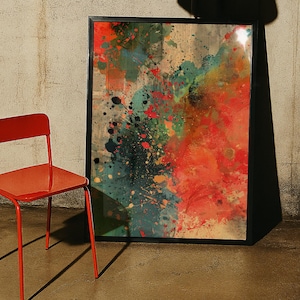 Puede incluir: Una pieza de arte mural rectangular enmarcada que presenta una composición abstracta de salpicaduras y lavados de pintura en rojo vibrante, verde azulado y negro. La obra está en un marco negro fino junto a una silla de metal roja.