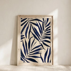 Könnte beinhalten: Ein gerahmter Wandkunstdruck mit einem Muster aus dunkelblauen Palmblättern auf hellcremefarbenem Hintergrund. Das Kunstwerk ist in einen hellen Holzrahmen mit einem einfachen, geradlinigen, rechteckigen Rahmendesign eingefasst.