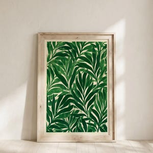 Puede incluir: Una pieza de arte mural enmarcada rectangular que presenta un patrón repetitivo de hojas de palmera verde oscuro pintadas en estilo acuarela sobre un fondo color crema, dentro de un marco de madera clara.