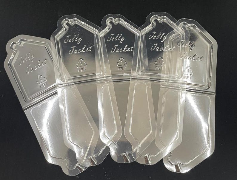 May include: Clear plastic "Jelly Jacket" packaging, featuring a house-shaped top with the text "Jelly Jacket" and a recycling symbol. The packaging is designed to hold a product, with a clear, transparent appearance.