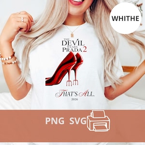 Puede incluir: Camiseta blanca con el texto "THE DEVIL WEARS PRADA 2" y un gráfico de tacones altos rojos. Debajo, el texto dice "THAT'S ALL. 2026". La camiseta tiene cuello redondo.