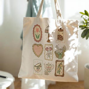 May include: Cream-colored tote bag featuring various illustrations in a vintage style. The designs include a tulip, a heart, a lamp, a jar of cookies, a bouquet of roses, a chicken in a basket, a teacup, a teapot, and a lemon branch.