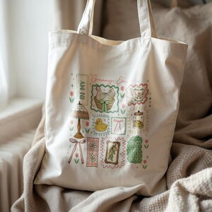 May include: Off-white tote bag with a charming vintage-style design. The illustrations include a lamp, a chicken in a basket, a teacup, a jar of cookies, and a duckling. The text "Granny Era" and "In My" are also visible on the bag.