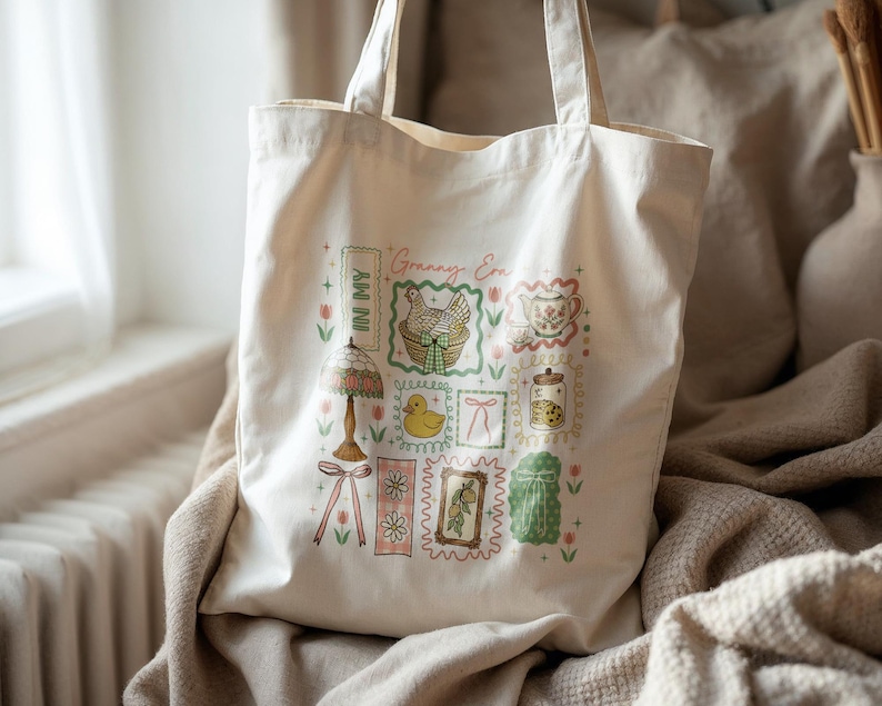 May include: Off-white tote bag with a charming vintage-style design. The illustrations include a lamp, a chicken in a basket, a teacup, a jar of cookies, and a duckling. The text "Granny Era" and "In My" are also visible on the bag.