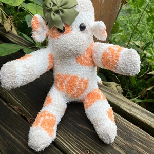 Mono de peluche suave hecho a mano: blanco con calabazas naranjas otoñales y lazo verde.
