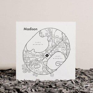 Pu&ograve; includere: Una mappa in bianco e nero di Madison, Wisconsin, con il testo "Madison" in alto. La mappa mostra le principali strade, i laghi e i quartieri della citt&agrave;. La mappa &egrave; stampata su un foglio di carta bianco.