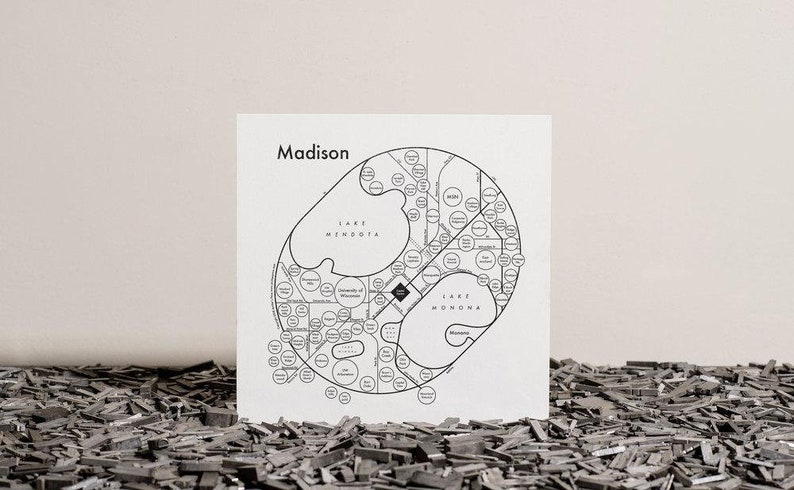 Pu&ograve; includere: Una mappa in bianco e nero di Madison, Wisconsin, con il testo "Madison" in alto. La mappa mostra le principali strade, i laghi e i quartieri della citt&agrave;. La mappa &egrave; stampata su un foglio di carta bianco.