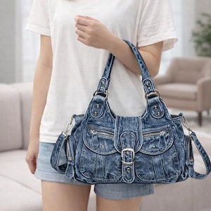 以下が含まれることがあります： 複数のポケット、ジッパー、バックル留めが付いたデニムハンドバッグ。 バッグには2つのハンドルと取り外し可能なショルダーストラップが付いています。 デニムは色あせた青色で、バッグは新品のようです。