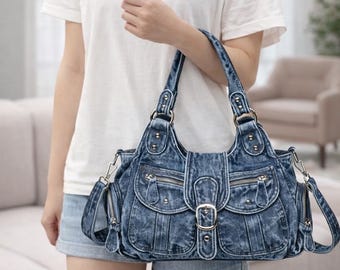 May include: A denim handbag with multiple pockets, zippers, and a buckle closure. The bag has two handles and a detachable shoulder strap. The denim is a faded blue color, and the bag appears to be new.