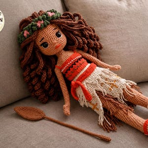 May include: A handmade crochet doll with brown hair, wearing an orange and white outfit, and a green floral crown. The doll is lying on a gray surface next to a brown crochet paddle. The image includes a PDF pattern digital download icon.