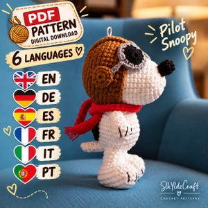 May include: A crochet amigurumi figure of a white dog wearing a brown aviator hat, gray goggles, and a red scarf. The text reads PDF PATTERN DIGITAL DOWNLOAD, 6 LANGUAGES, Pilot Snoopy, and SlhYldzCraft CROCHET PATTERNS with heart icons.