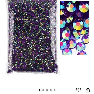 Puede incluir: Una bolsa transparente llena de pedrer&iacute;a Clear Dk.amethyst AB. Las piedras son peque&ntilde;as, redondas y facetadas, con un acabado iridiscente brillante. Un primer plano muestra las variaciones de color de las piedras, incluyendo morado, amarillo y rosa.