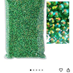 Puede incluir: Una bolsa de pl&aacute;stico transparente llena de pedrer&iacute;a verde esmeralda AB. Un primer plano muestra las gemas redondas y facetadas con reflejos iridiscentes. El color se describe como Esmeralda AB.
