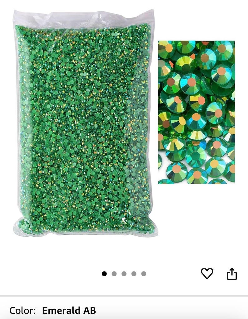 Puede incluir: Una bolsa de pl&aacute;stico transparente llena de pedrer&iacute;a verde esmeralda AB. Un primer plano muestra las gemas redondas y facetadas con reflejos iridiscentes. El color se describe como Esmeralda AB.