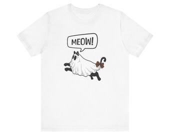May include: White t-shirt featuring a cartoon cat dressed as a ghost. The cat is black and white with a brown bow on its tail. A speech bubble above the cat says "MEOW!" in black text. The shirt is a casual, everyday wear item.