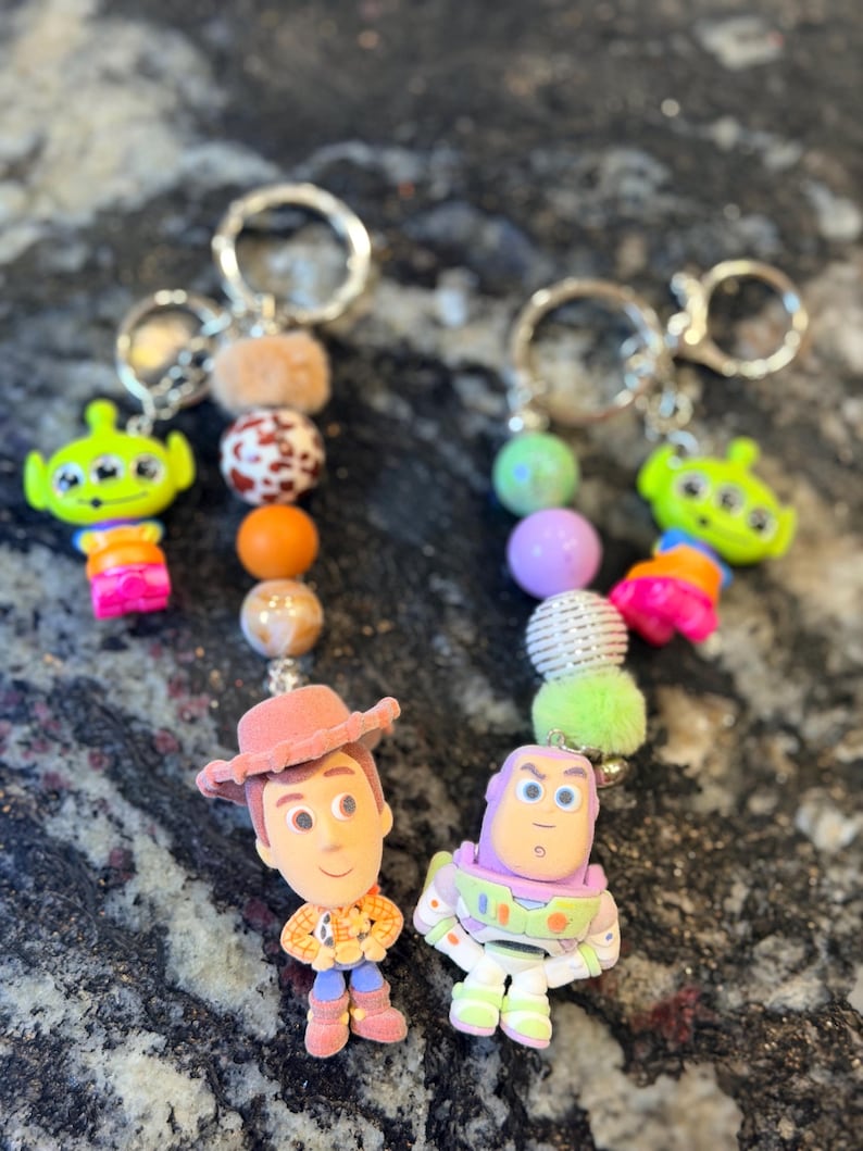 Pu&ograve; includere: Due portachiavi con personaggi del film Toy Story. Un portachiavi ha una figura di Woody e l'altro una figura di Buzz Lightyear. Ogni portachiavi ha una serie di perline colorate e un portachiavi argentato.