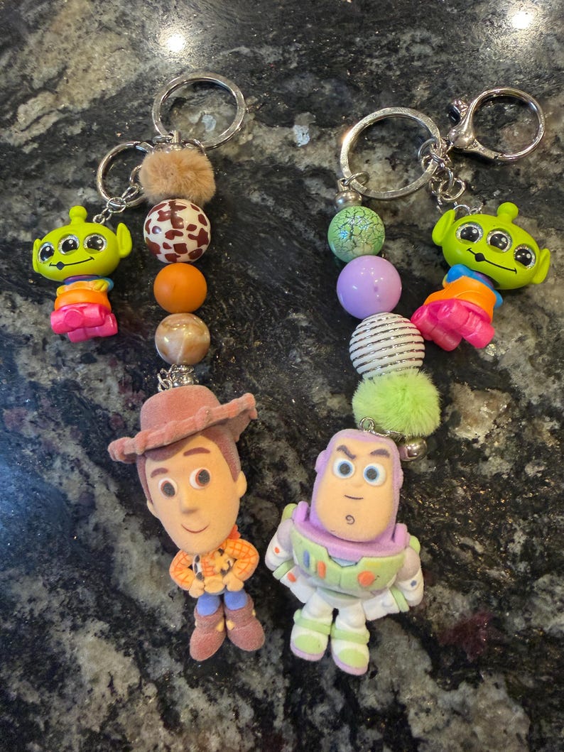 Pu&ograve; includere: Due portachiavi con personaggi del film Toy Story. Un portachiavi ha una figura di Woody e l'altro una figura di Buzz Lightyear. Ogni portachiavi ha perline decorative e un portachiavi argentato.