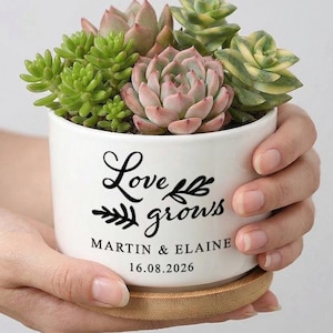 Puede incluir: Una taza de cerámica blanca con un asa negra y el texto "But First, Coffee" en negrita negra. La taza está sobre una superficie de madera. La taza mide 10 cm de alto.