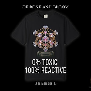 May include: Black t-shirt with a geometric design of diamonds and gold lines. The text "0% TOXIC 100% REACTIVE" is printed below the design. The shirt also has the text "SPECIMEN SERIES" and "OF BONE AND BLOOM".