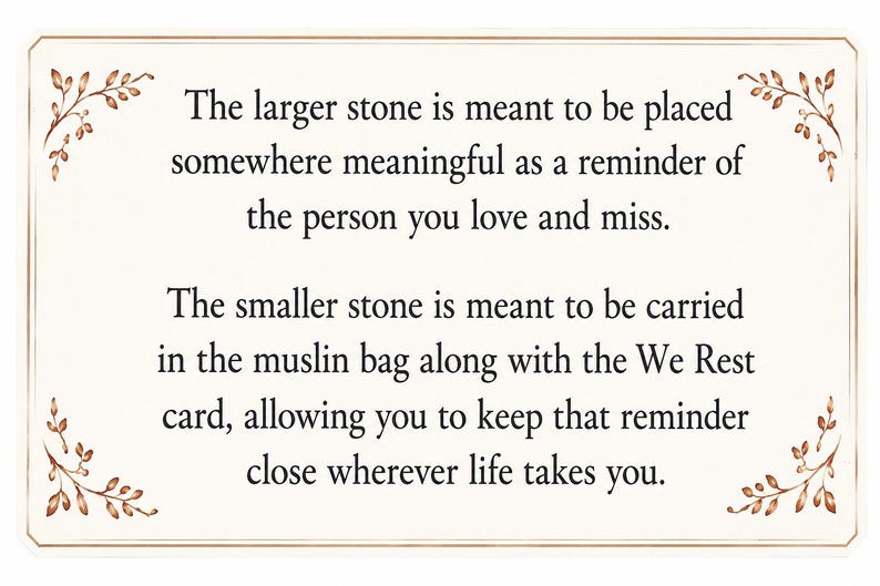 May include: A rectangular card with a cream background and brown leaf illustrations in the corners. The text reads: The larger stone is meant to be placed somewhere meaningful as a reminder of the person you love and miss. The smaller stone is meant to be carried in the muslin bag along with the We Rest card, allowing you to keep that reminder close wherever life takes you.