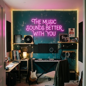 Puede incluir: Un estudio de música en casa con una pared verde azulado y un letrero de neón que dice "THE MUSIC SOUNDS BETTER WITH YOU". La habitación cuenta con un teclado, una guitarra, discos y paneles insonorizantes. Una guirnalda de luces enmarca la pared.