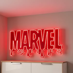 Puede incluir: Un letrero de neón rojo con la palabra "MARVEL" y un efecto de goteo. El letrero está montado en una pared de color neutro sobre un mueble blanco. Las letras están delineadas en blanco, creando un efecto brillante.