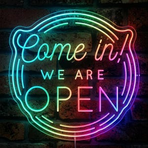 May include: A circular neon sign featuring a gradient of rainbow colors. The text reads Come in, WE ARE OPEN in a combination of cursive and block lettering. The sign is framed by three concentric circular lines that follow the circular shape.