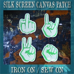 May include: Four white canvas patches with green outlines, each displaying a different hand gesture: a middle finger, a rock-and-roll sign, a peace sign, and a clenched fist. The text SILK SCREEN CANVAS PATCH and IRON ON / SEW ON is visible.