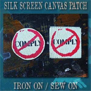 May include: Two silk screen canvas patches featuring the word COMPLY in black text. One patch is circular and the other is square. Both patches display a red circle with a diagonal line through it over the text. The edges are frayed.