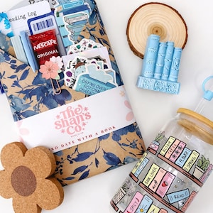Peut inclure: Un coffret cadeau sur le thème des livres avec une pochette à motifs floraux, des autocollants, du café et un journal de lecture. Comprend un dessous de verre en liège en forme de fleur, une tranche de bois, une décoration de livre bleue et un verre avec un design de bibliothèque.