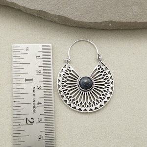 May include: Silver-toned, openwork earrings with a dark blue center stone. The earrings have a half-moon shape with intricate, symmetrical cut-out designs. The earrings measure approximately 1.5 inches in length.