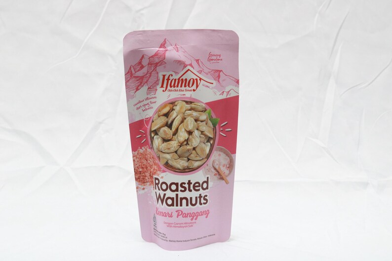 Puede incluir: Una bolsa rosa de nueces tostadas. La bolsa presenta la marca "Ifamoy" y las palabras "Roasted Walnuts" en letras grandes. La bolsa tambi&eacute;n tiene una ilustraci&oacute;n de nueces y una cordillera.