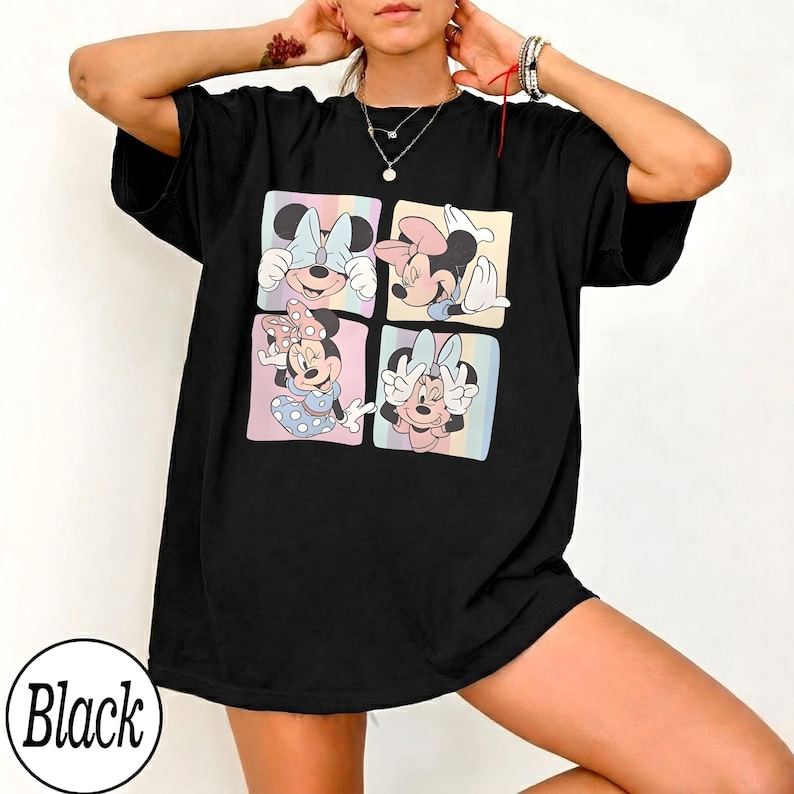 May include: Black t-shirt featuring a colorful graphic of Minnie Mouse in four different poses. Each pose is set within a pastel-colored square. The word "Black" is printed in a white circle at the bottom.