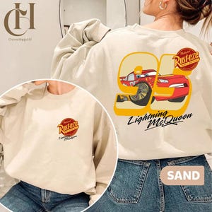 以下が含まれることがあります： 映画「カーズ」のライトニング・マックィーンのグラフィックが特徴のベージュのスウェットシャツ。デザインには、黄色の数字95、「Lightning McQueen」の文字、Rustezeのロゴが含まれています。スウェットシャツは長袖です。