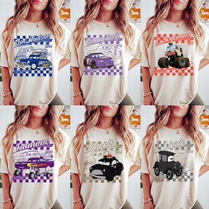 May include: A collection of six beige t-shirts, each featuring a different cartoon car design. The designs include Doc Hudson, Bobby Swift, T-Screamer, Ramone, Sheriff, and Lizzie, with text and checkered flag backgrounds. The shirts are displayed on a person.