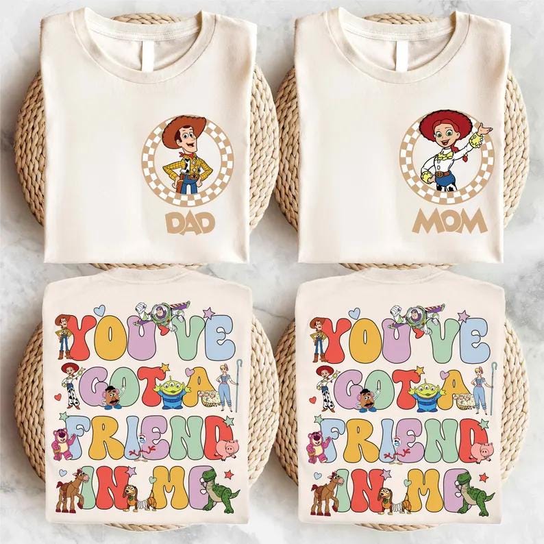 May include: Four cream-colored t-shirts. Two shirts have a Woody and Jessie cartoon design with the words "DAD" and "MOM". The other two shirts have the text "YOU'VE GOT A FRIEND IN ME" with cartoon characters.