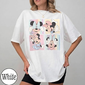 May include: White t-shirt featuring a colorful graphic of Minnie Mouse in four different poses. Each pose is set against a pastel-colored background. The shirt has a relaxed fit and short sleeves.