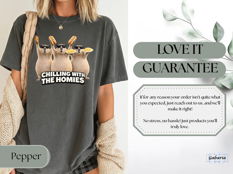 K&ouml;nnte beinhalten: Dunkelgraues T-Shirt mit einer Grafik von drei Cartoon-Wasserschweinen mit Sonnenbrillen und Essen. Der Text "CHILLING WITH THE HOMIES" steht darunter. Das Shirt hat eine lockere Passform.