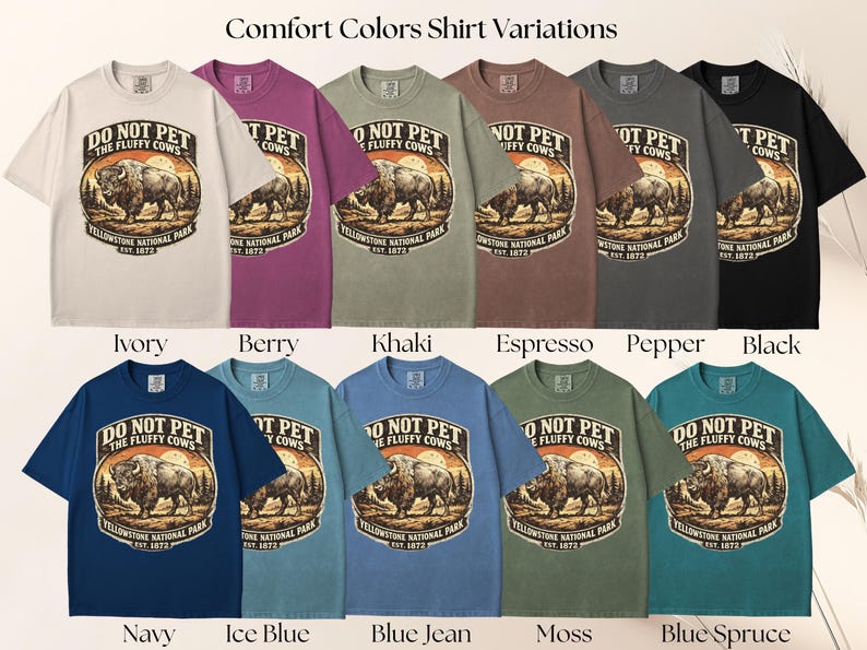May include: A collection of Comfort Colors t-shirts in various colors, each featuring a graphic with a bison and the text "DO NOT PET THE FLUFFY COWS" and "Yellowstone National Park EST. 1872". Colors include ivory, berry, khaki, espresso, pepper, black, navy, ice blue, blue jean, moss, and blue spruce.