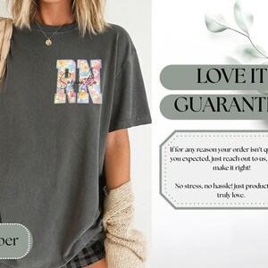 May include: Dark gray t-shirt with the letters "RN" in a floral design and the name "Samantha" in script. The shirt has a relaxed fit and is made of a soft material. The word "Pepper" is at the bottom.