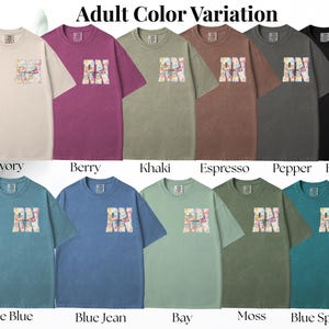 May include: A collection of short-sleeved t-shirts in various colors, including ivory, berry, khaki, and black. Each shirt features a colorful graphic design with the letters "RN" on the front. The text "Adult Color Variation" is at the top.